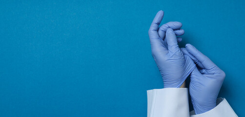 Doctor hands in medical gloves on blue background