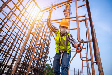 Asian worker working at height equipment constructive at construction site. Fall arrestor device for worker with hooks for safety body harness on selective focus.