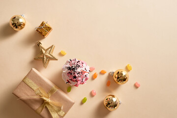 Christmas card. Cupcake with gift boxes, ornament and candies on light yellow background. Holidays.