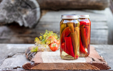 Chili peppers in a glass jar on a wooden table, homemade pickles