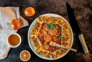 Homemade red blood orange galette with mint and honey. Fruit bakery. Healthy vegetarian dessert. Open pie, orange tart.