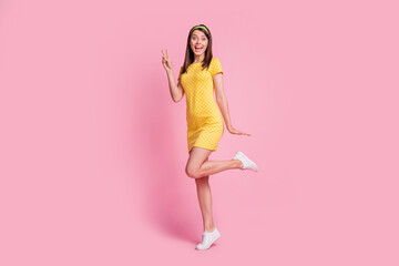 Fototapeta na wymiar Full length body size view of pretty thin cheerful girl jumping having fun showing v-sign isolated over pink color background