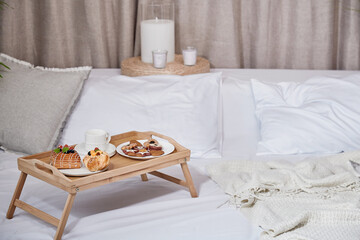 Breakfast in bed on a wooden table. Morning coffee, fruits and pastries