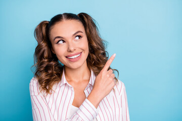 Portrait of lovely cheerful brown-haired girl demonstrating copy empty blank space advert isolated over vivid blue color background