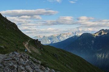 A girl is walking along a path into the mountain