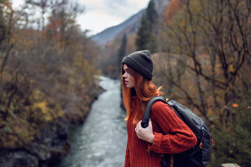 woman with backpack admires the river in the mountains nature