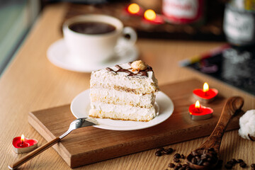 Slice of creamy cake on decorated table with coffee