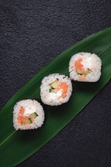 Classic sushi rolls on a bamboo green leaf on a dark background