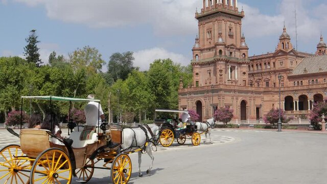 Beautiful Espana Square, in the center of Seville. Pandemic time , with very few tourists. Horse-drawn carriage passing. Camera still and slowly tilt up to the tower.