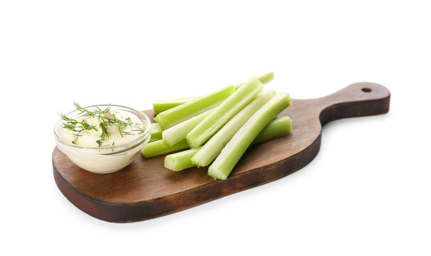 Wooden board with dip sauce and celery sticks isolated on white