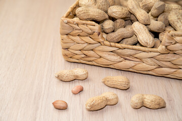 peanuts unpeeled in a basket on a wooden background