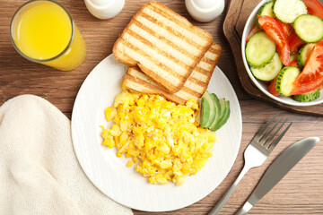 Delicious breakfast with scrambled eggs served on wooden table, flat lay