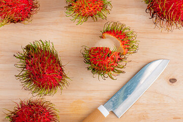 Rambutan fruit and knives on wooden table background 