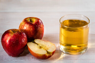 Sliced apple. One glass of apple juice with red apples in the sunset background. Nice white wood table. Summer day. Good mood.