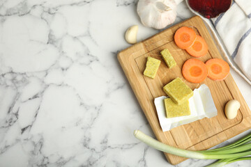 Bouillon cubes and other ingredients on white marble table, flat lay. Space for text