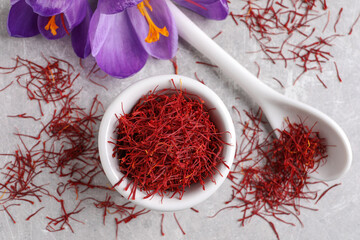 Dried saffron and crocus flowers on grey table, flat lay