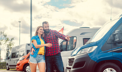 Couple looking for camper or RV on yard of dealer