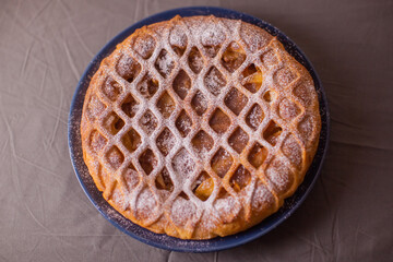 Round pie with pear filling. The dough mesh is decorated.
