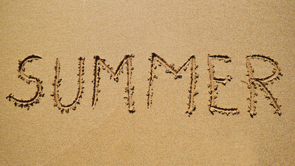 Summer - an inscription on the sand by the ocean.