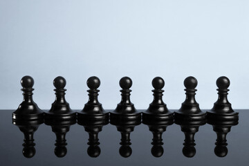 line, a row, a crowd of black chess pieces of pawns. Leadership concept. Black and white