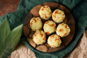 baked rolls with mozzarella and parmesan cheese cap on a wooden board decorated with bamboo leaves