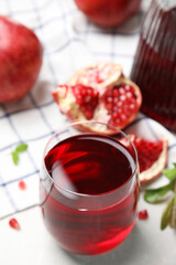 Glass of pomegranate juice and fresh fruits on white table