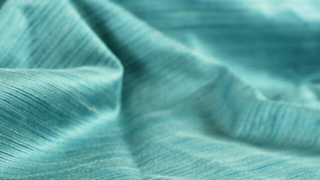 Dolly shot close up detailed cloth texture of green shiny cloth. Continuous circular elastic weave material.