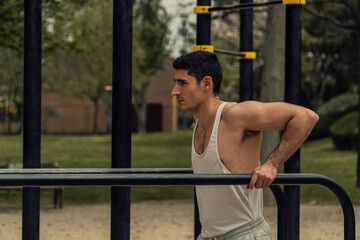 HOMBRE HACIENDO EJERCICIO DE FONDOS, HOMBRE ENTRENANDO EN LAS BARRAS DEL PARQUE, MUSCULOSO CON CAMISETA BLANCA, ENTRENAMIENTO DE BRAZOS