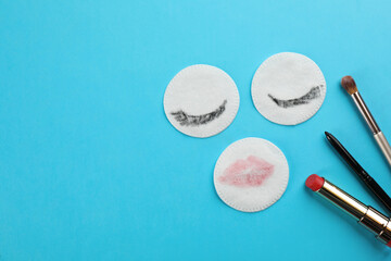 Dirty cotton pads, brush and cosmetic on turquoise background, flat lay. Space for text