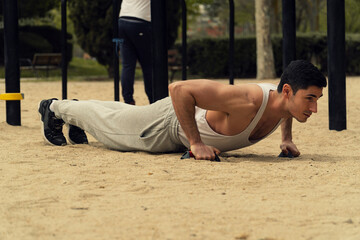 JOVEN DEPORTISTA HACIENDO FLEXIONES, HACIENDO EJERCICIO AL AIRE LIBRE, HOMBRE MUSCULOSO CON...