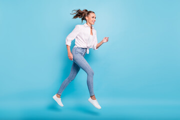 Obraz premium Full length body size profile side view of lovely sporty cheerful girl jumping running action isolated on bright blue color background