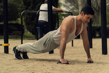 Obraz premium JOVEN DEPORTISTA HACIENDO FLEXIONES, HACIENDO EJERCICIO AL AIRE LIBRE, HOMBRE MUSCULOSO CON CAMISETA BLANCA