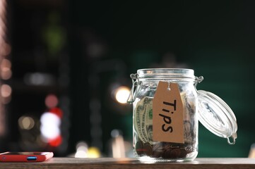 Glass jar with tips on wooden table indoors. Space for text