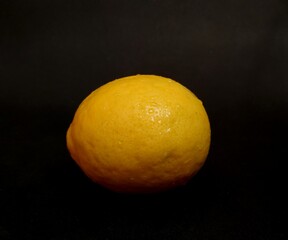 Fresh lemon in pretty yellow on black background