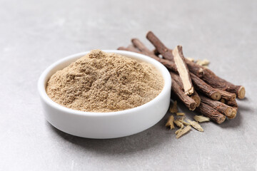 Dried sticks of liquorice root and powder on grey table, closeup