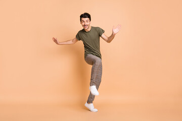 Fototapeta na wymiar Full length body size photo of dancing guy enjoying party in checkered pants smiling isolated on pastel beige color background