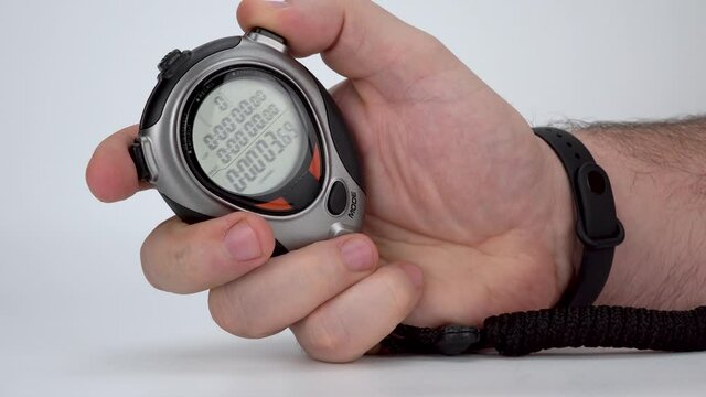 electronic sports stopwatch in a mans hand. launching the e-manual stopwatch. digital time counter on a white background. movement of time