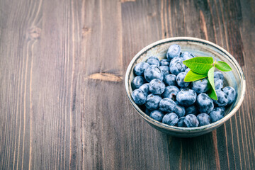 Bowl of fresh ripe blueberry on rustic wooden table with copy space for your text