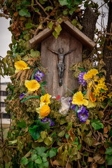 przydrożna kapliczka z krucyfiksem przystrojona kwiatami  - obrazy, fototapety, plakaty
