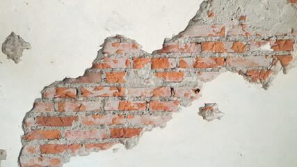 The cracked white wall clearly shows the bricks on the wall.