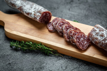Fuet Salami cut in slices. Traditional Spanish sausage on wooden board. Fuets Catalan dry sausages. Top view