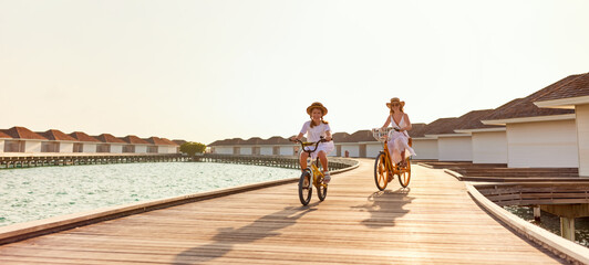 Carefree mother and daughter riding bicycles along wooden promenade