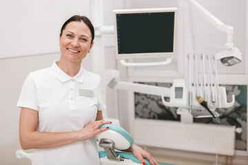 Cheerful professional dentist smiling joyfully,standing at her dental office, copy space