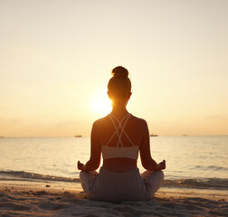 Calm woman meditating on beach at sunset - obrazy, fototapety, plakaty