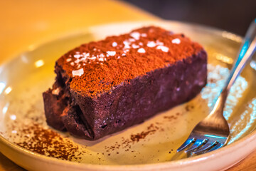 Chocolate sliced cake with icing on tablecloth