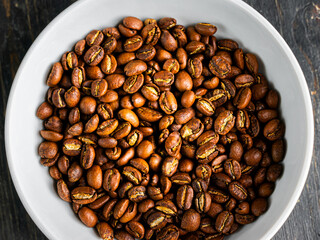 Coffee beans in a bowl on a wooden background. Roasted black coffee in a dish. 