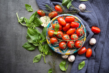 Cherry tomatoes, basil leaves, garlic bulbs, herbs and pepper on a table. Bruschetta ingredients top view photo. Gray textured background with copy space. Traditional Italian food. 