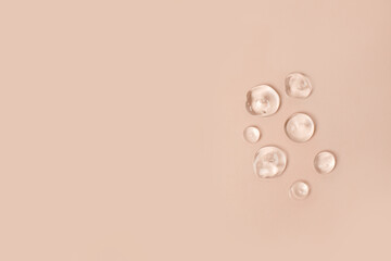 Lotion transparent gel drops texture background, Close-up drops transparent cosmetic aloe vera gel on neutral beige background with copy space. Body care and skin care, moistirize