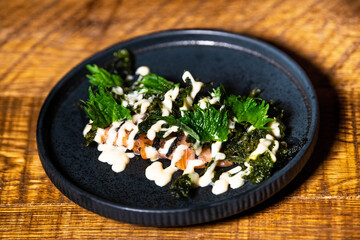 Cooked salmon with kale salad on top, topped with mayonnaise on a dark platter