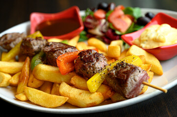 Pork skewers with vegetables topped with potatoes and salad